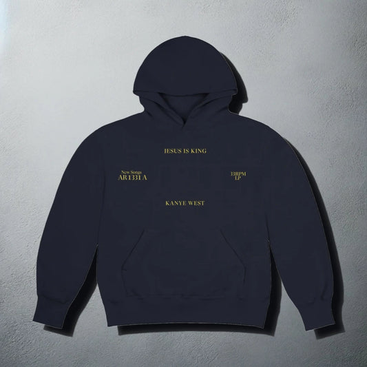 A dark navy hoodie with subtle gold text that reads 'JESUS IS KING' and 'KANYE WEST' on the chest. The hoodie is designed with a hood, long sleeves, and a front pouch pocket, exuding a minimalist and stylish aesthetic