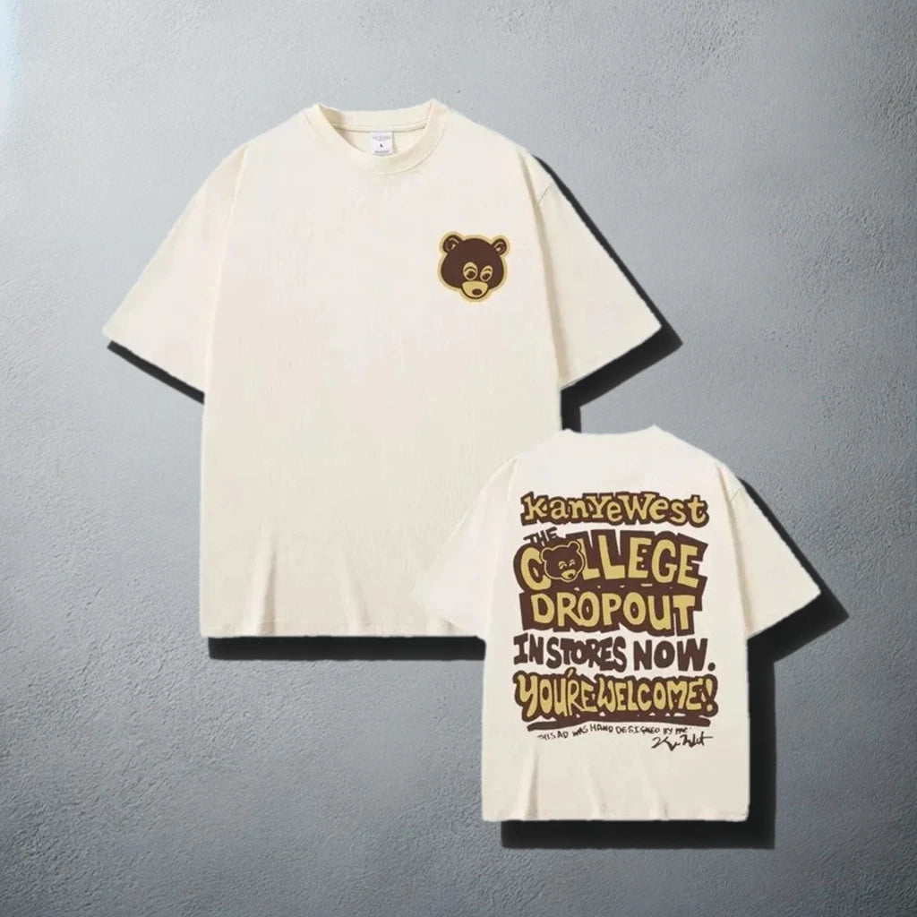 A stylish Beige t-shirt, featuring a small brown bear logo on the front left chest area and a bold graphic on the back that reads 'Kanye West The College Dropout In Stores Now. You're Welcome!' with a playful font design, reminiscent of Kanye West's debut album promotional material.