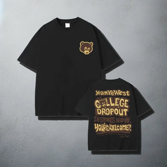 A stylish black t-shirt, featuring a small brown bear logo on the front left chest area and a bold graphic on the back that reads 'Kanye West The College Dropout In Stores Now. You're Welcome!' with a playful font design, reminiscent of Kanye West's debut album promotional material.