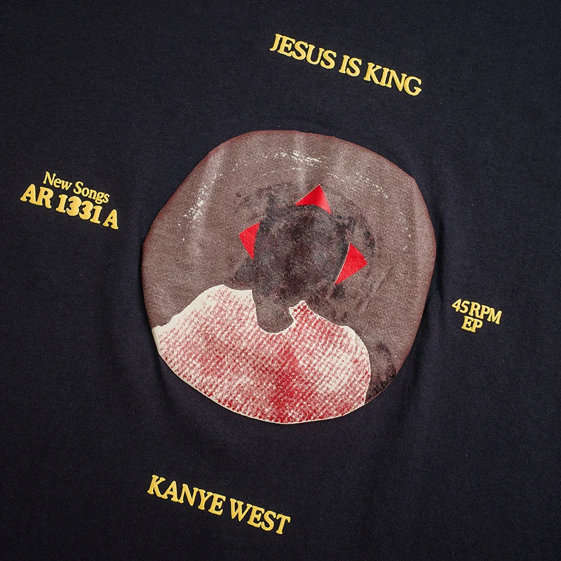 Close up of the print of Navy blue t-shirt featuring the 'Jesus is King' album art with vinyl record design, showcasing Kanye West's iconic bear mascot in a crown.