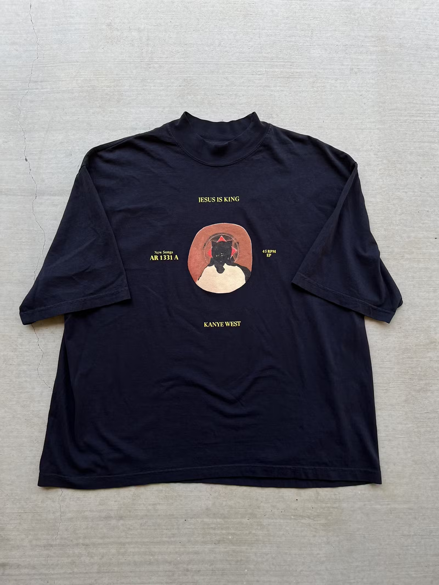 Navy blue t-shirt featuring the 'Jesus is King' album art with vinyl record design, showcasing Kanye West's iconic bear mascot in a crown, emphasizing the album's gospel influence.