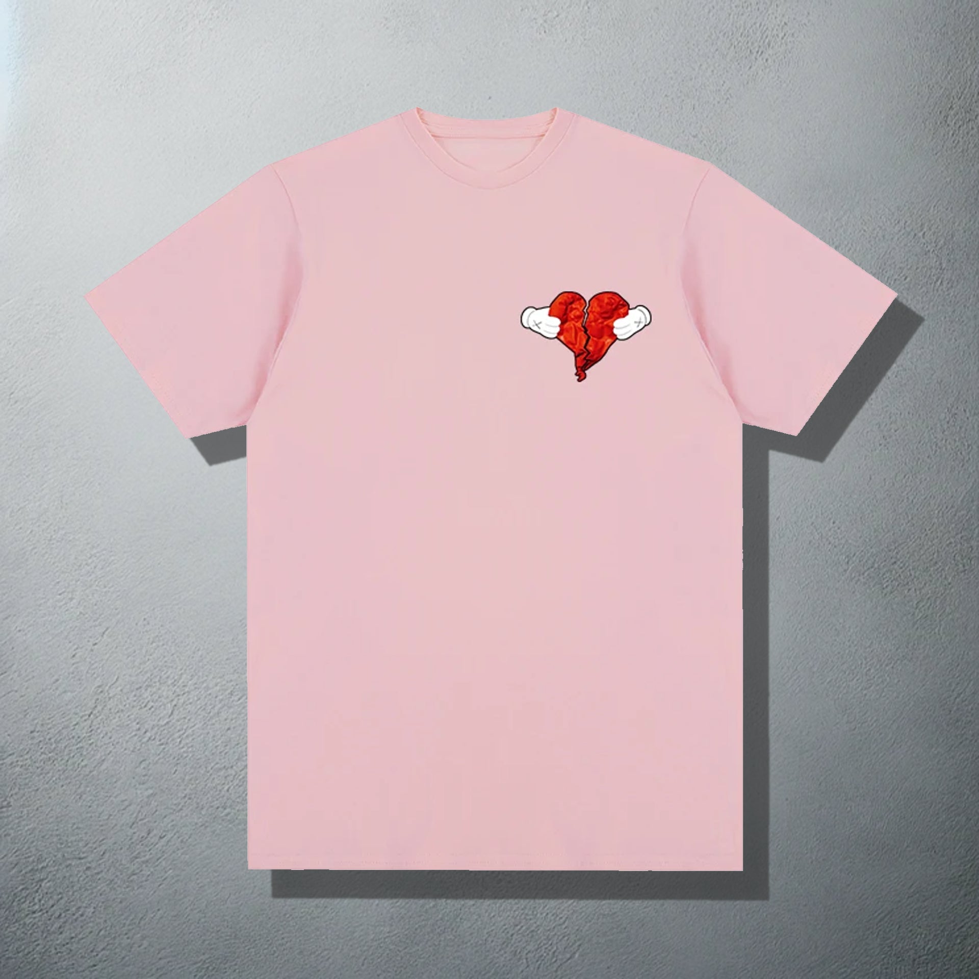 Pink T-shirt featuring a 'Heartless' inspired red heart with wings graphic, referencing Kanye's '808s & Heartbreak' album