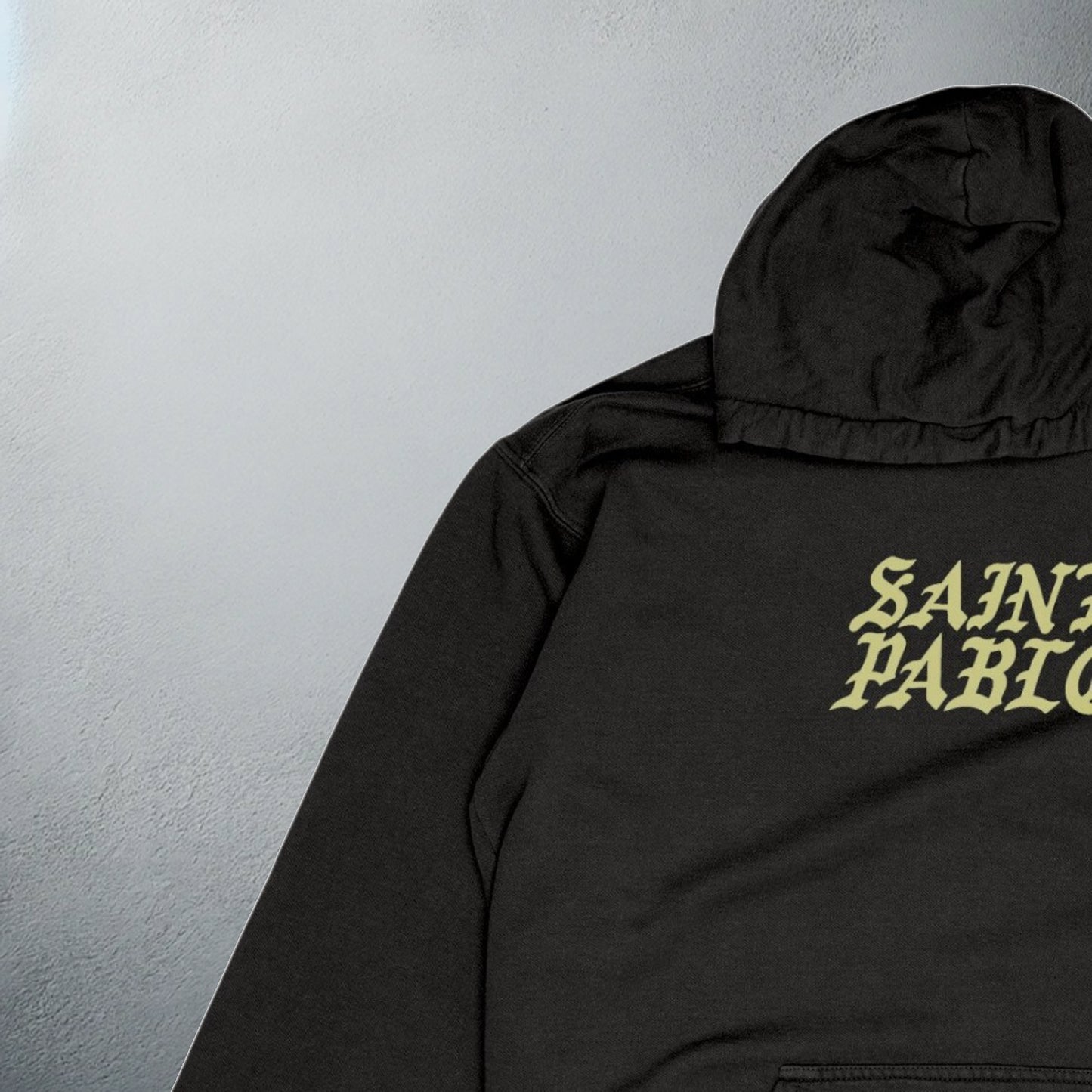 close up of Black 'Saint Pablo' tour hoodie with bold yellow text on the front, for Kanye merchandise