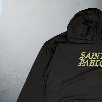 close up of Black 'Saint Pablo' tour hoodie with bold yellow text on the front, for Kanye merchandise